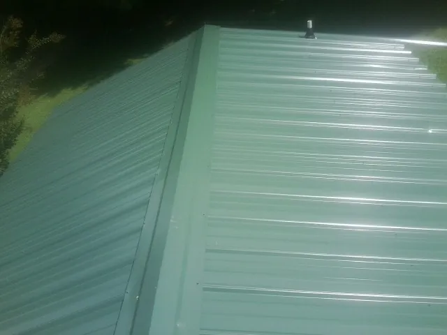 New green metal panels meeting at the ridge of a roof — Flat Roof Repair work by our crew in Elkton