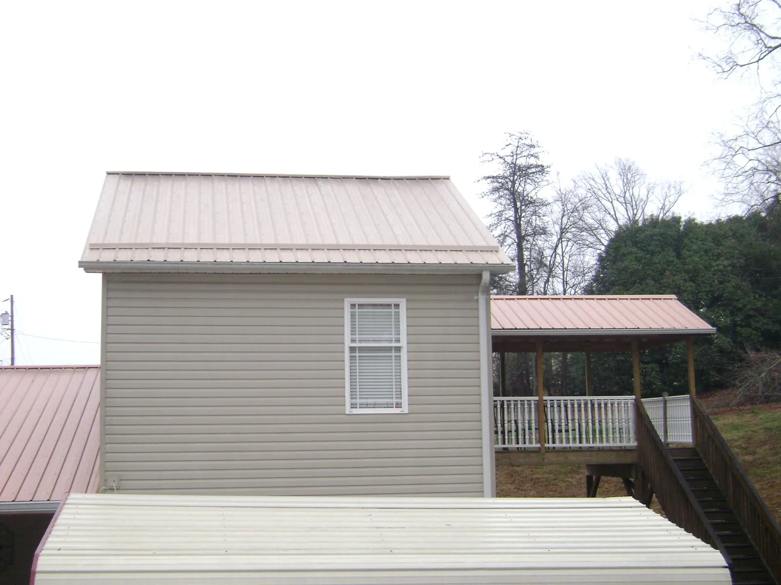 Tan metal roofs on a two story addition and attached porch, from a Roof Replacement job in Elkton